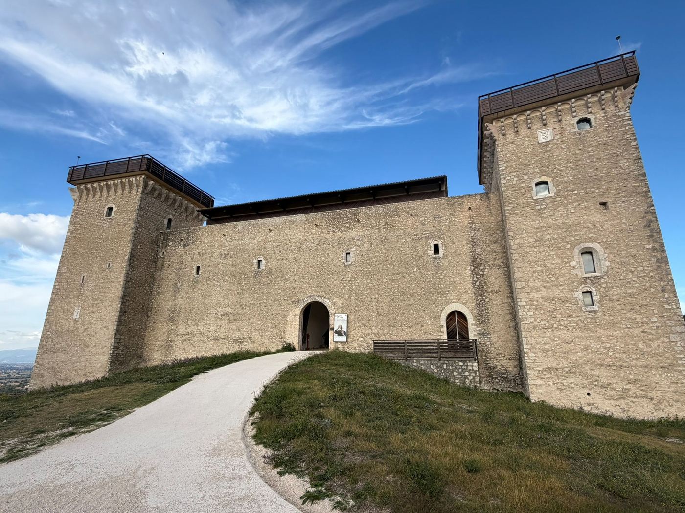 The towers and entrance of the Rocca Albornoziana under a blue sky